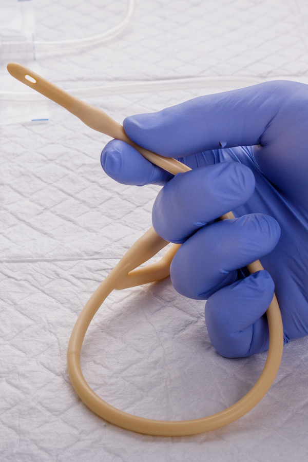 Close-up of a healthcare professional holding a Foley catheter, used in urinary drainage, demonstrating device structure for medical device testing.
