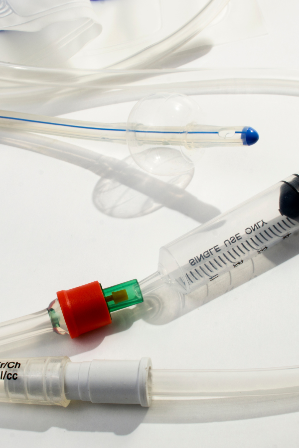 Close-up of a Foley catheter with balloon, syringe, and drainage components, illustrating urological device setup for urinary catheter testing and compliance.