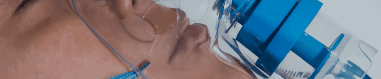 Patient wearing a breathing mask connected to a respiratory gas pathway device.