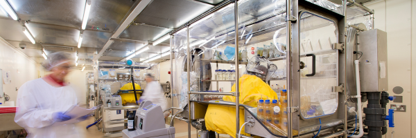 Sterility testing isolator in a pharmaceutical microbiology laboratory with scientists performing sterile product testing.
