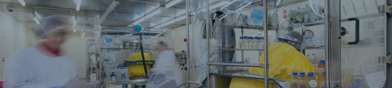 Scientists performing sterility testing in a pharmaceutical and medical device microbiology laboratory using isolators and controlled cleanroom equipment.