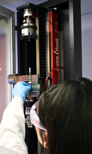 Lab technician operating a Zwick Roell universal tensile testing machine with a pre-filled syringe